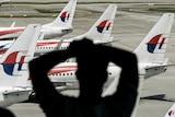 A man looks through a window at Malaysia Airlines' aircraft parked on the tarmac at Kuala Lumpur International Airport.