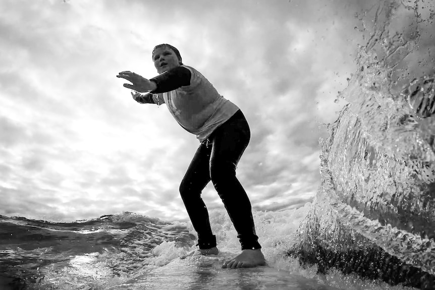 Black and white action shot of boy on surfboard from camera-mounted camera