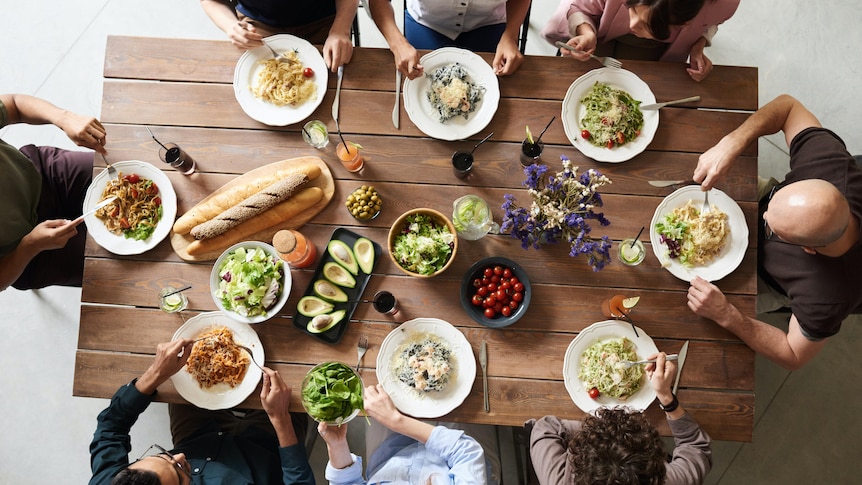 An aerial shot of a group of people sitting around a dining table full of food. 