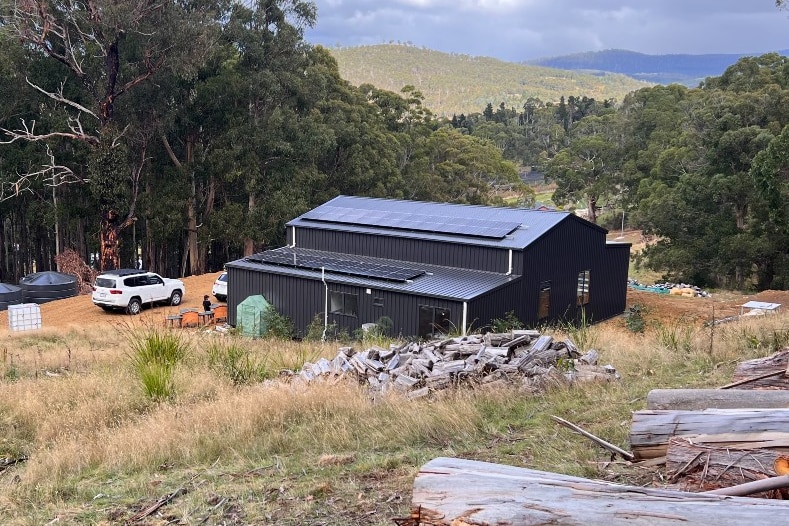 A house made of black steel sits in a paddock 