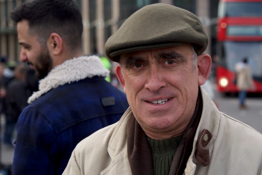 A man wearing an olive-green hat looks into the camera in London.