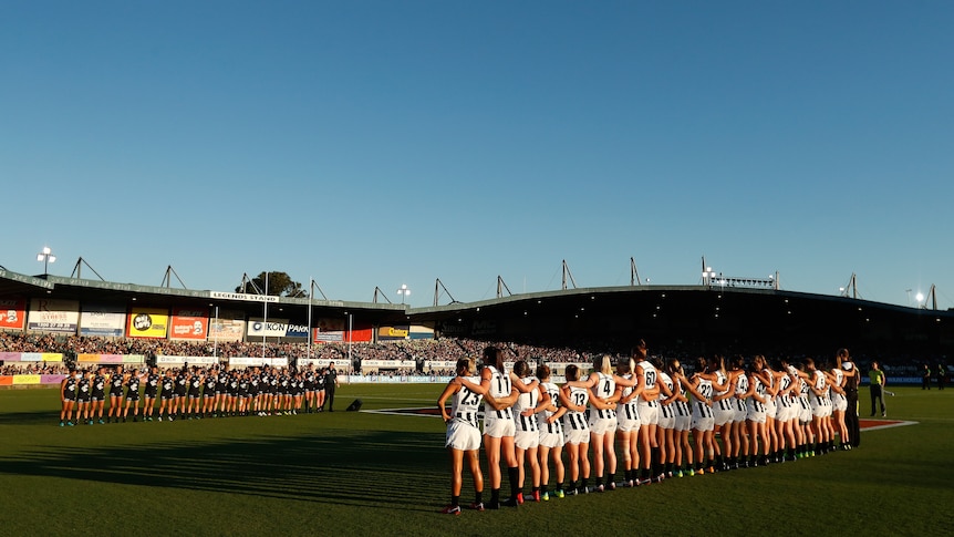 Carlton and Collingwood players line up for the national anthem at the opening AFLW game in 2018