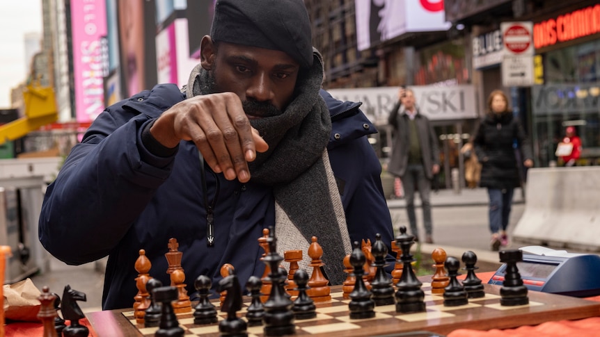 A man with his hand lifted about a chess board. 