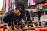 A man with his hand lifted about a chess board. 