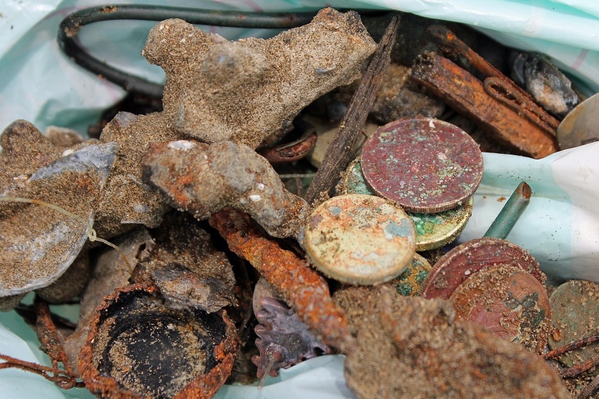 Collection of hooks, bobby pins, and other rusted metal items collected on the beach.