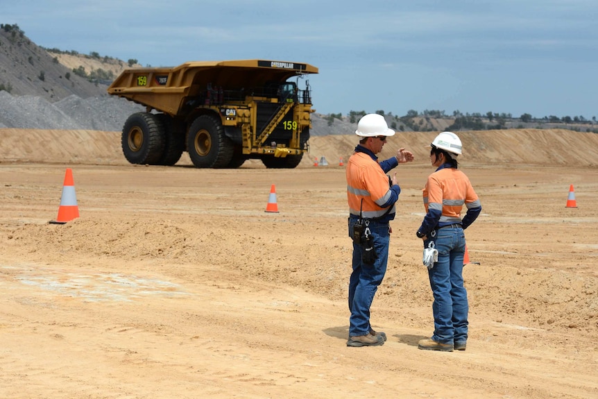 Two people in high vis stand on a mine site.