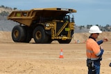 Workers stand at a mine site with trucks in central Queensland