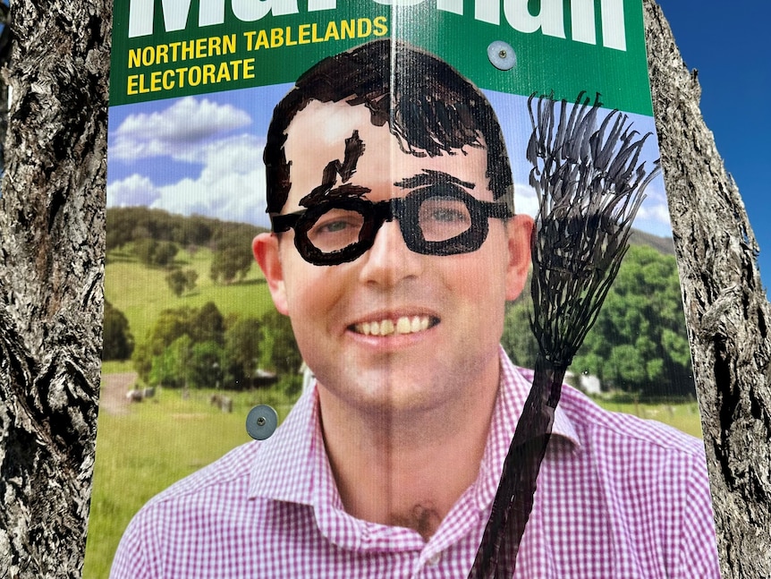 Election sign of man with black marker drawings of Harry Potter glasses, lightning bolt scar and broomstick.