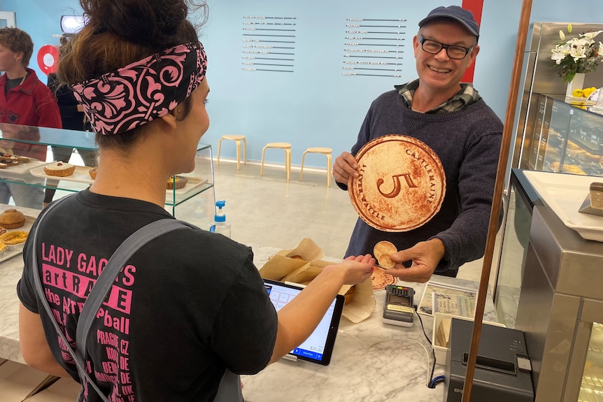 man paying for pies with clay coins