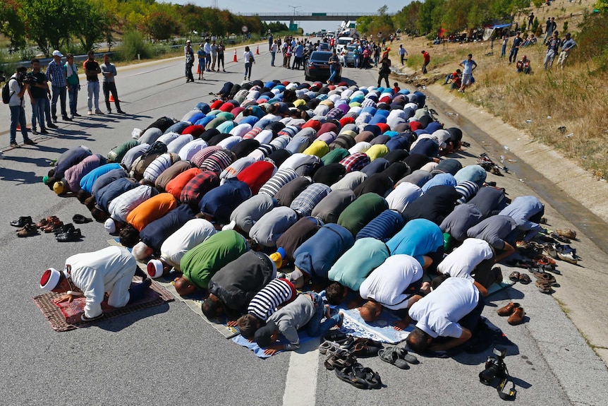 Asylum seekers pray on a highway near Edirne, Turkey