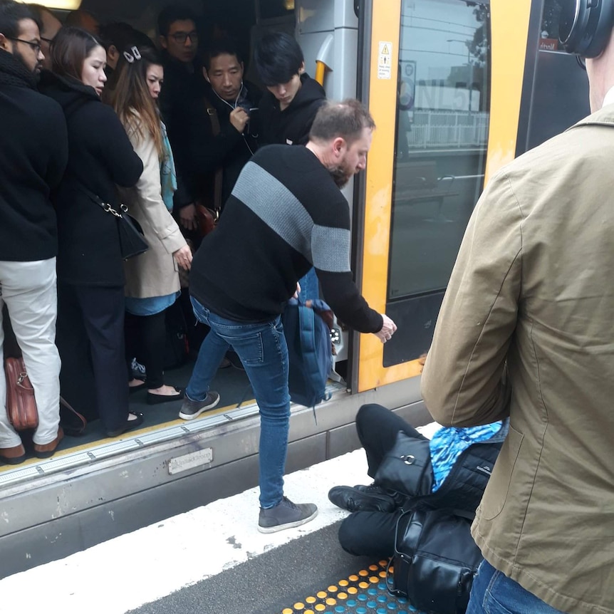A woman falls while people cram onto a train.