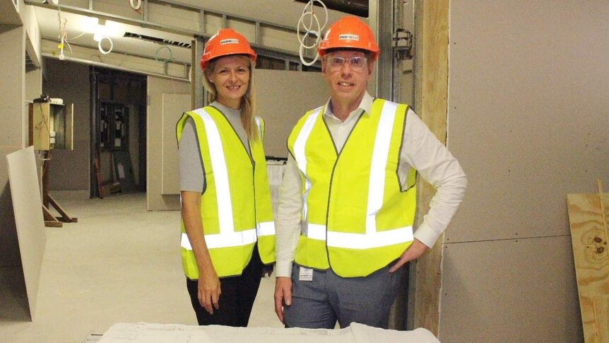 Man and woman stand in construction zone of a hospital.