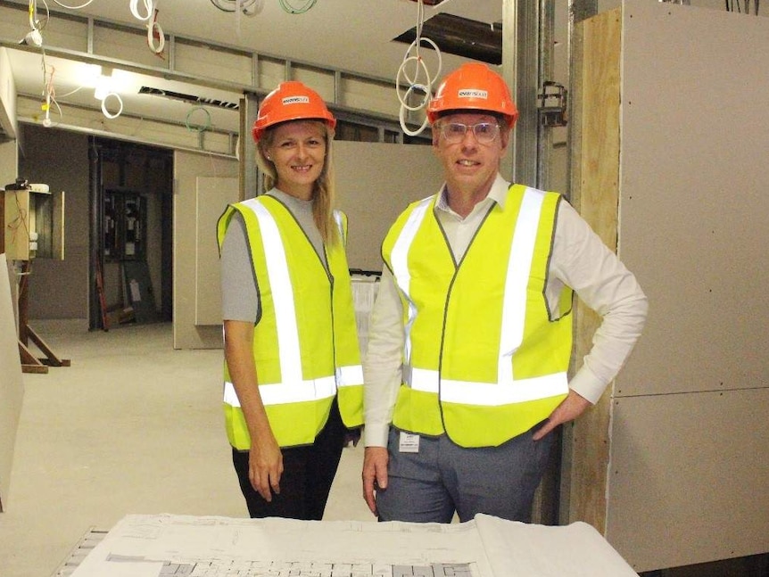 Man and woman stand in construction zone of a hospital.