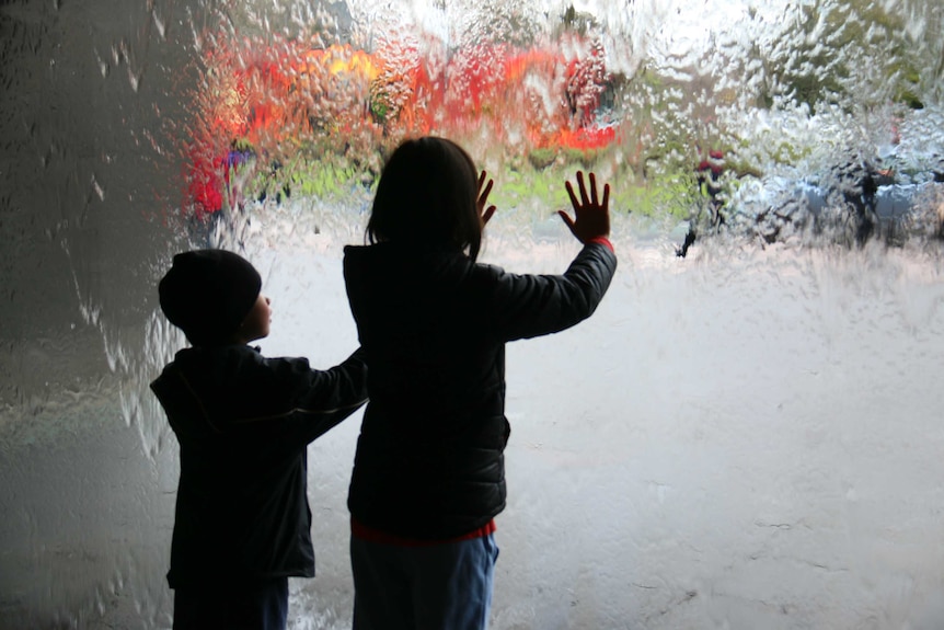Two children put their hands on a water wall
