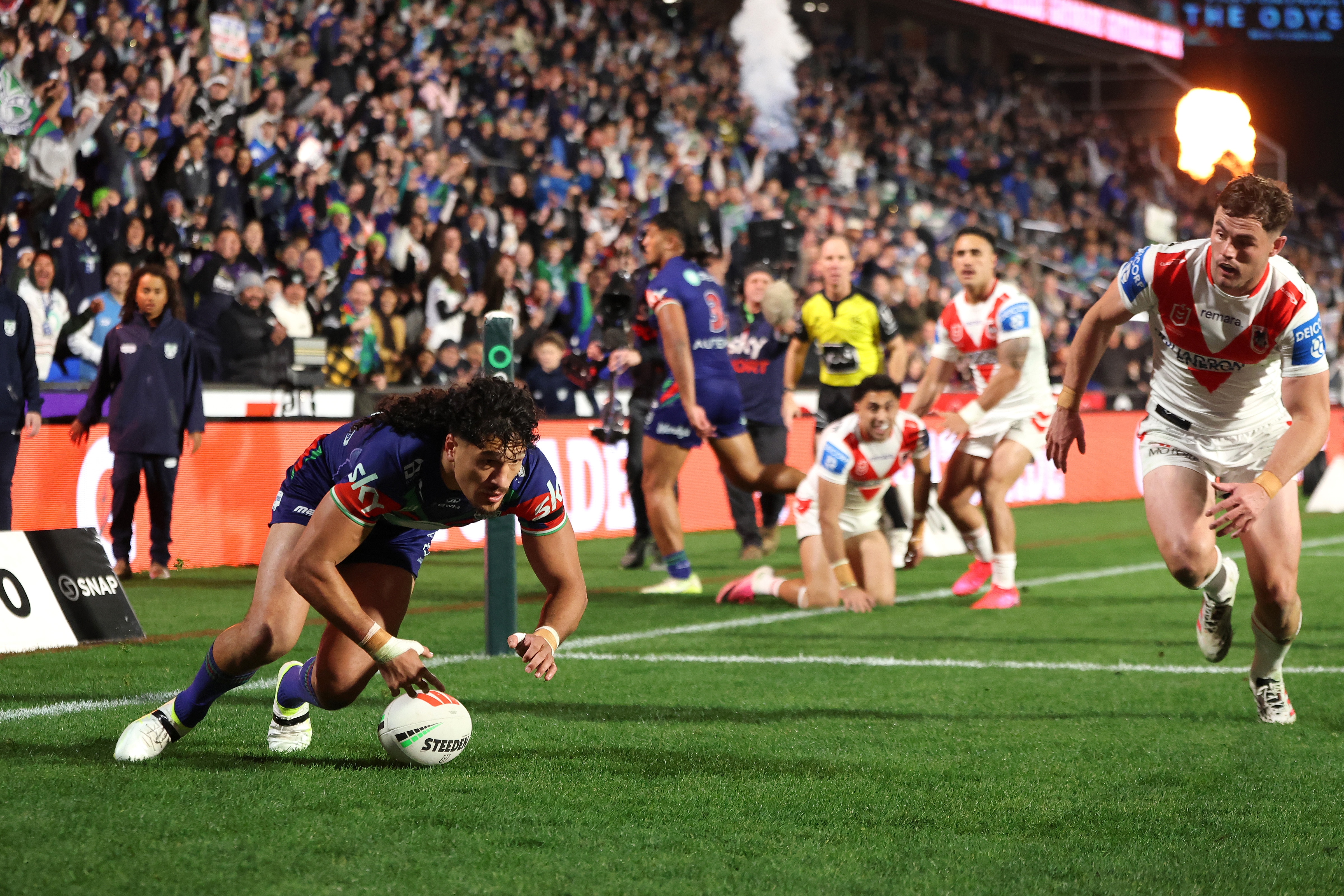 A rugby league player in blue and white scores a try