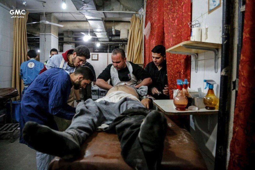 Syrian paramedics treat an injured man who was wounded by the shelling