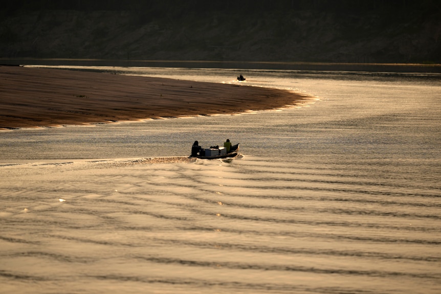 small boats move along the river at sunset