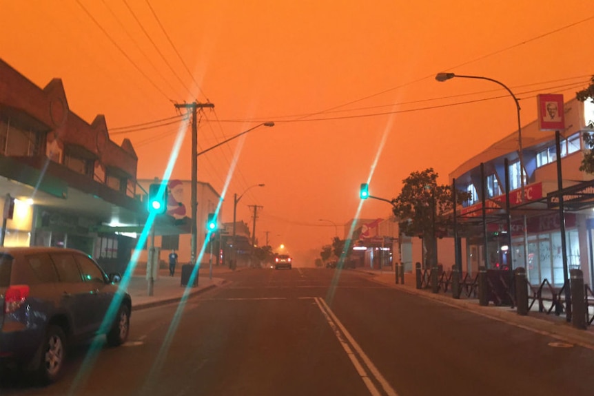 Main street with dark orange sky and street lights on.