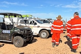 Men in SES uniforms walk past an all terrain vehicle and four wheel drives.