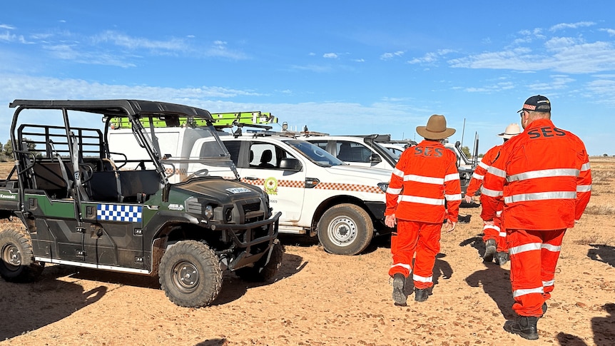 men in SES uniforms walk past an all terrain vehicle and four wheel drives