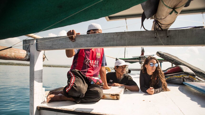 Two men and a woman relax at the bow of a fishing boat