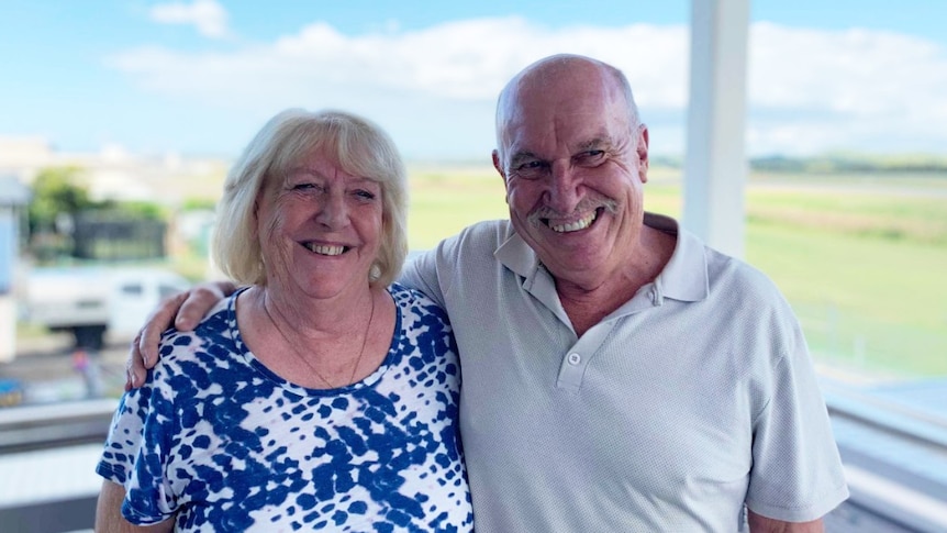 two old people on deck with airfield in background