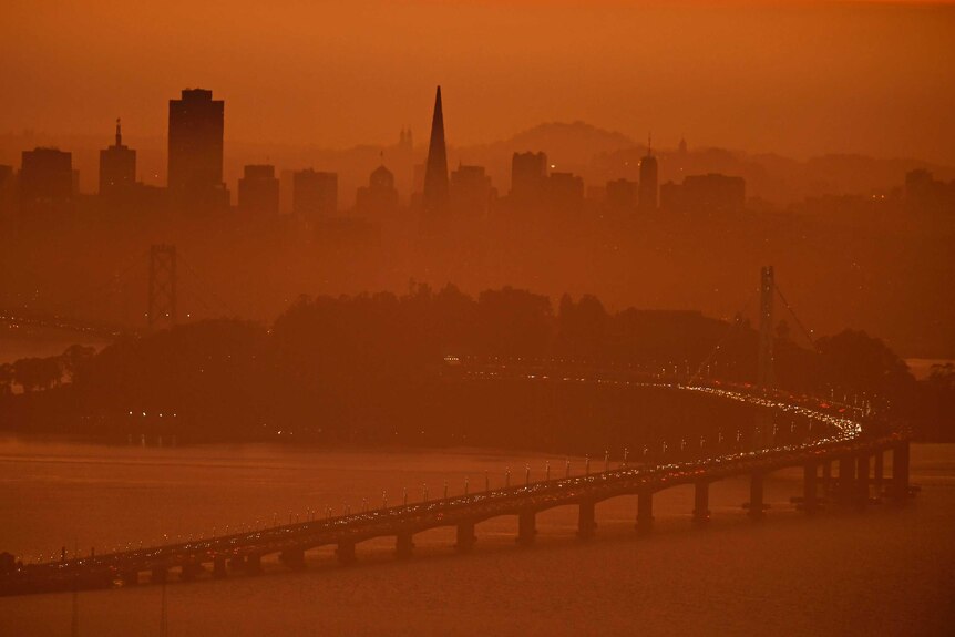 San Francisco skyline is covered in red light by fires.