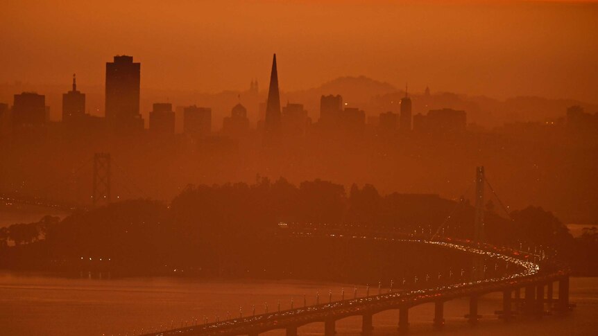 San Francisco skyline is covered in red light by fires.