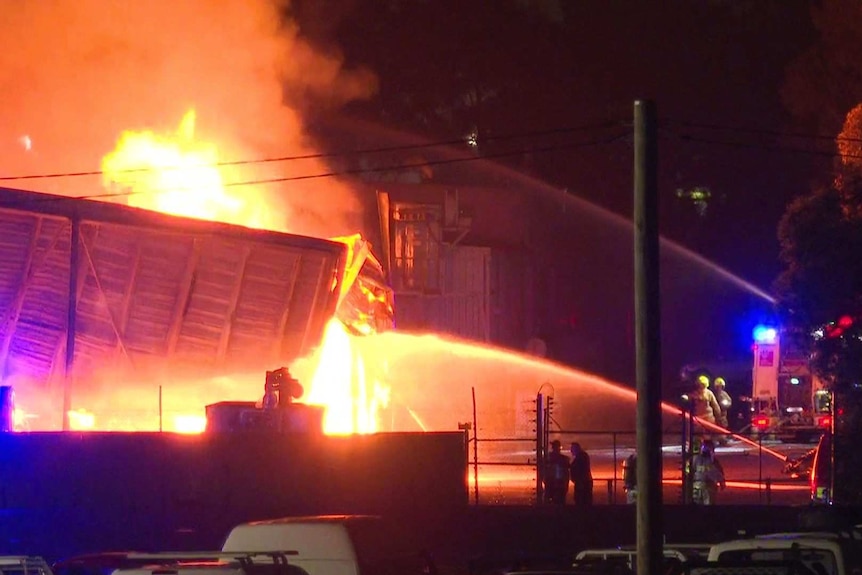 Two streams of water on a a large building on fire.