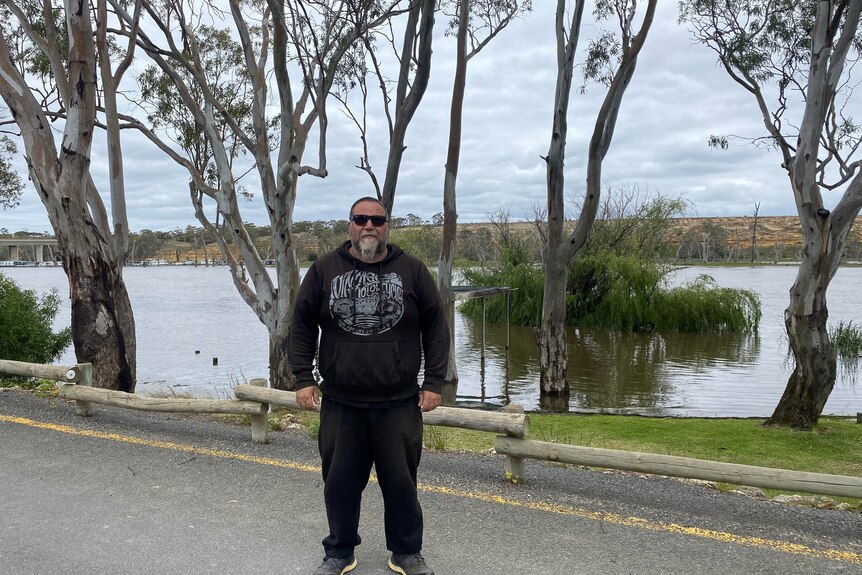 A man wearing sunglasses standing on road near the River Murray