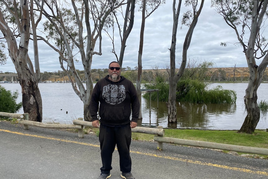 A man wearing sunglasses standing on road near the River Murray