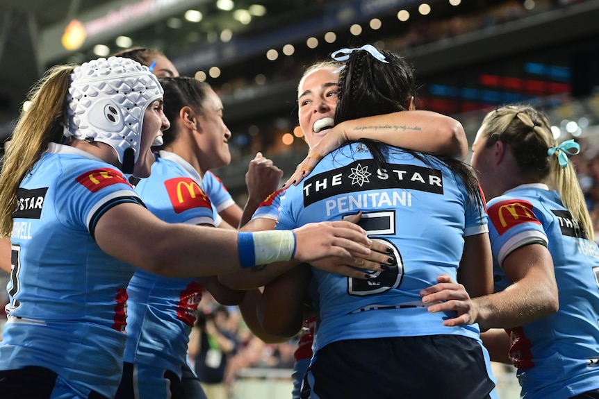 NSW Blues players hug after a try in the Women's State of Origin.