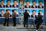 People look at a building covered in posters of Chinese President Xi Jinping.