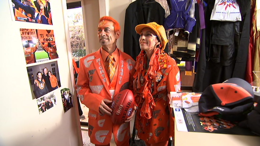 man and woman in room surrounded by orange AFL memorabilia