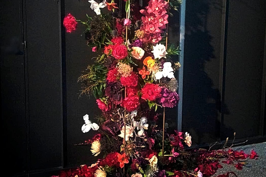 Brightly coloured flowers fall like a waterfall against a dark backdrop.