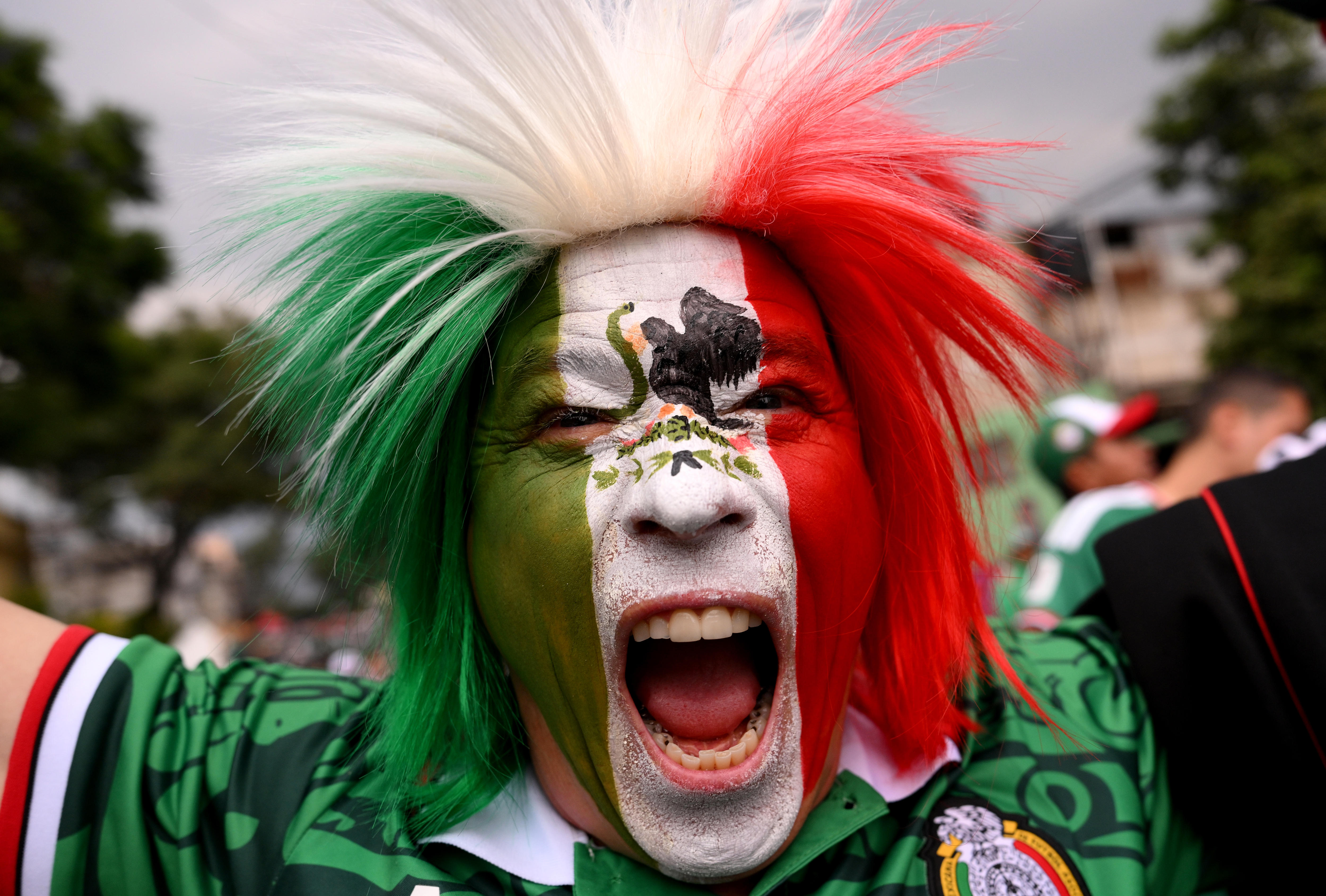 A Mexico fan roars while wearing facepaint and a coloured wig