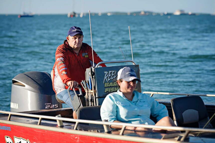 A photo of two people driving a boat