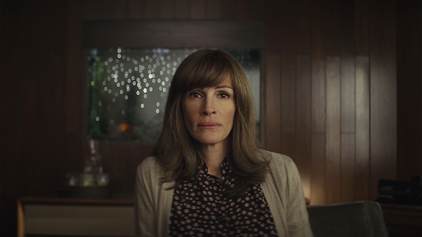 A brunette middle-aged woman looks concerningly into the camera, Julia Roberts in the Homecoming web TV series