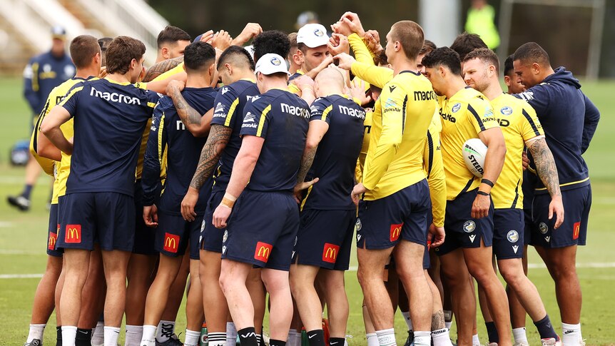 A group of rugby league players huddle together during a training session