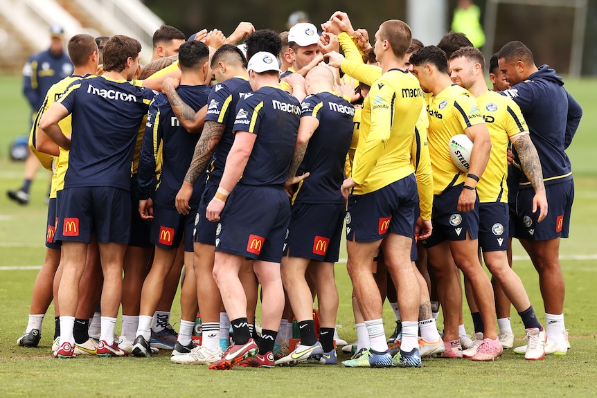A group of rugby league players huddle together during a training session