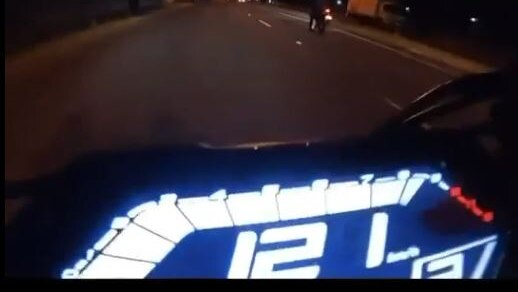 A motorcycle speedo at night showing 121 km/h