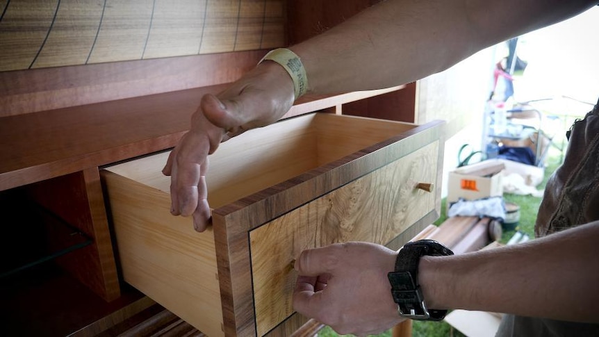 Hands pull open wooden drawer from cabinet