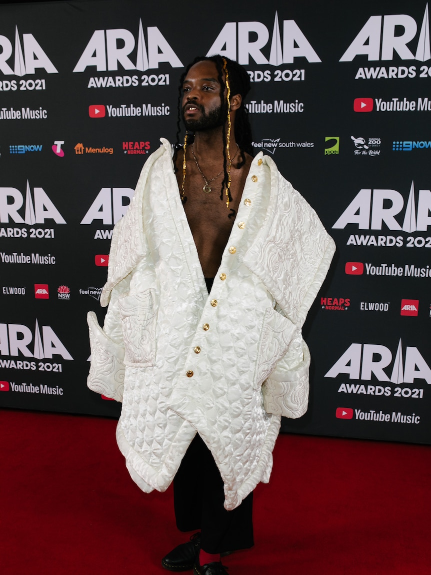 A man with long hair wearing a large white coat.