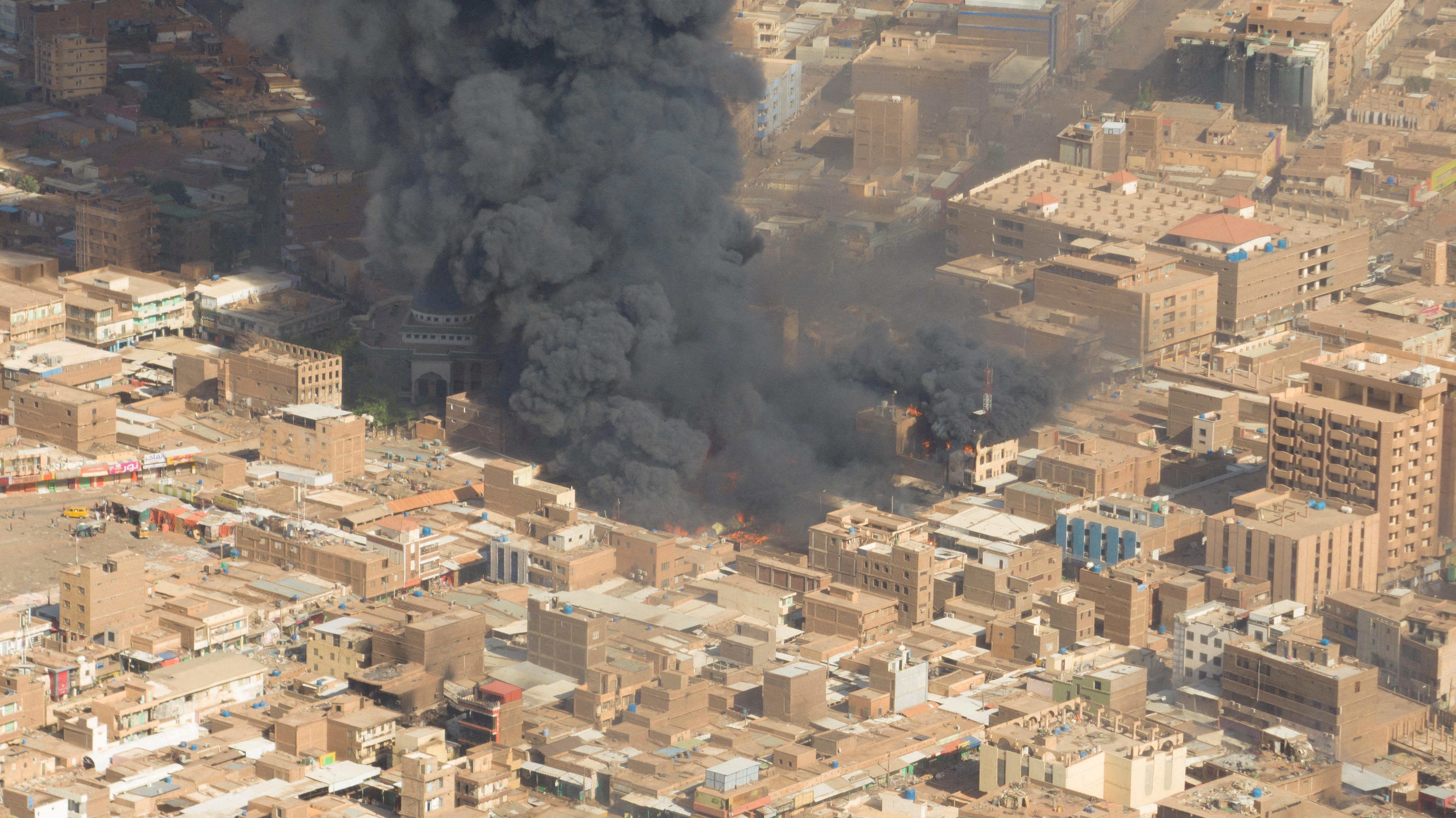 An aerial view shows black smoke and fire rises from a city centre