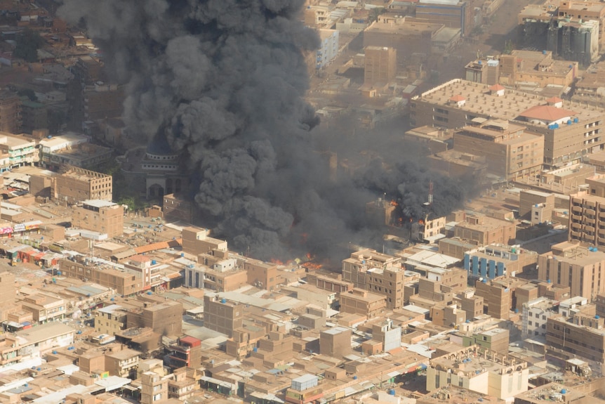 An aerial view shows black smoke and fire rises from a city centre