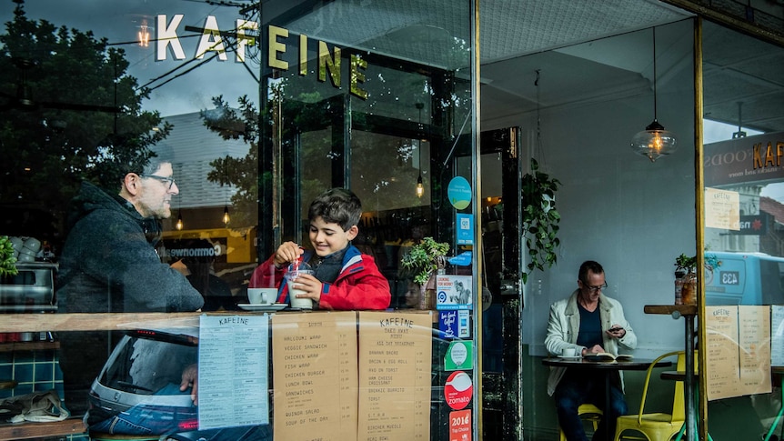 Outside a cafe looking through the window at a man and his son and other patrons