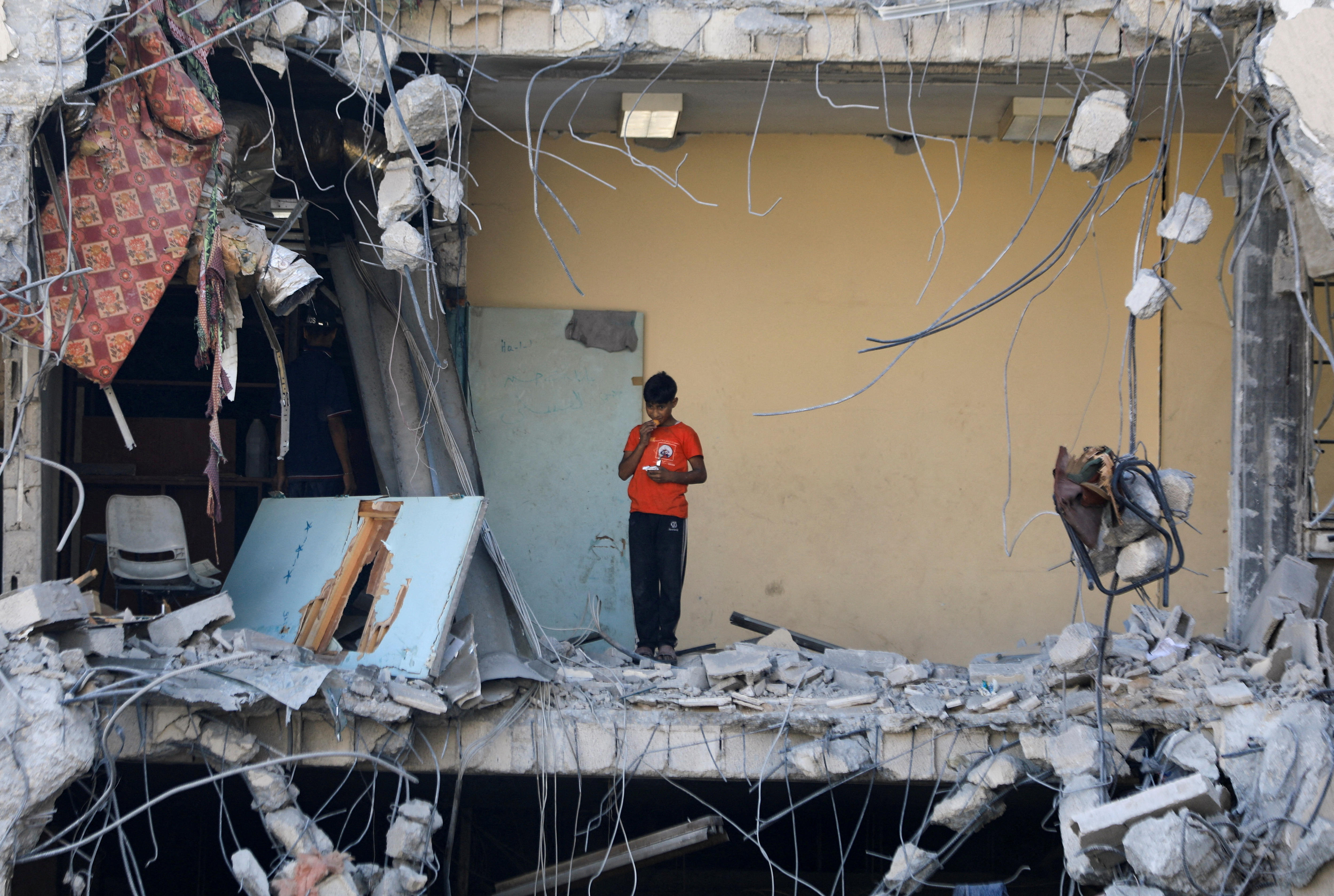 A boy stands in a ruined building.