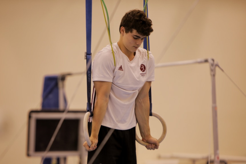 Young man pushing himself up on gymnastic rings.