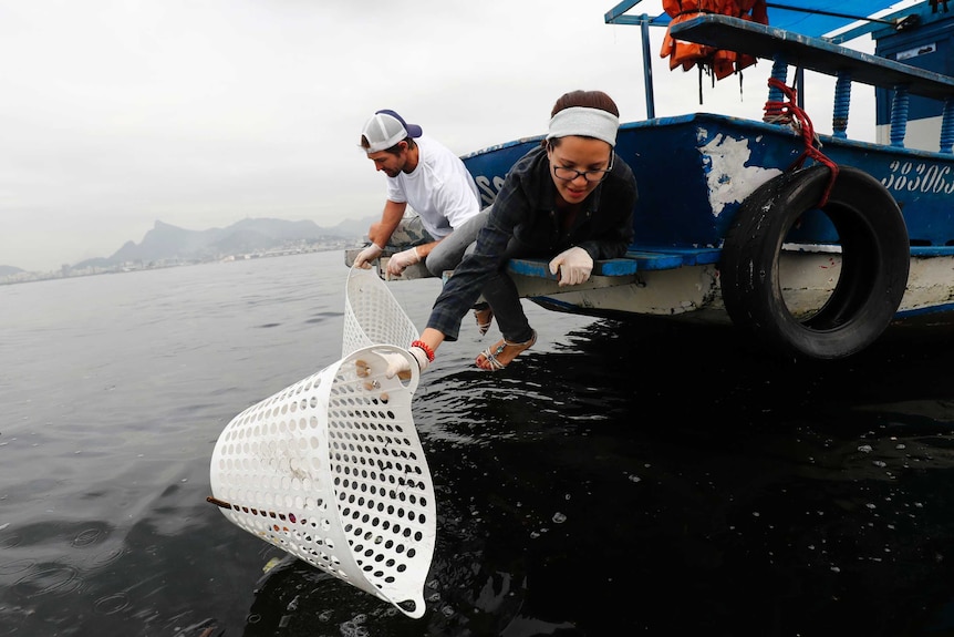 American sailor Brad Funk and Brazilian volunteer Camila Avelar collect garbage in the notoriously dirty Guanabara Bay.