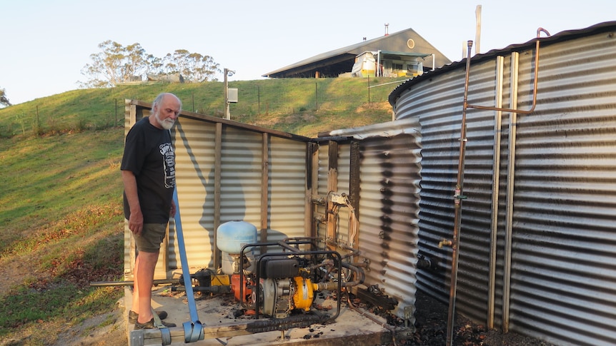 Man stands next to burnt water pump.